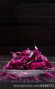 Red cabbage salad in a glass bowl and wooden background.. Red cabbage salad in a glass bowl and wooden background