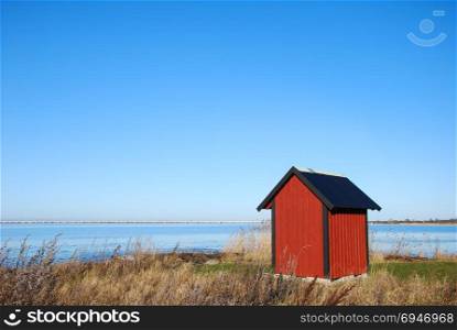Red cabin by the coast with the swedish Oland Bridge in the background