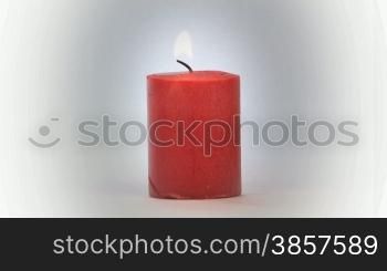 Red candle burning over a light background