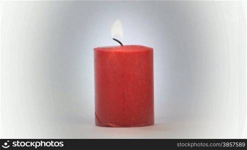 Red candle burning over a light background