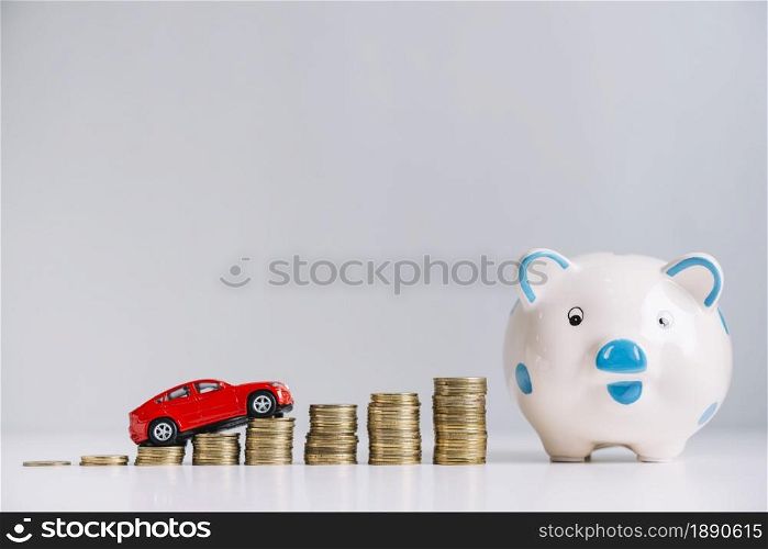 red car driving increasing stacked coins near piggybank . Resolution and high quality beautiful photo. red car driving increasing stacked coins near piggybank . High quality and resolution beautiful photo concept