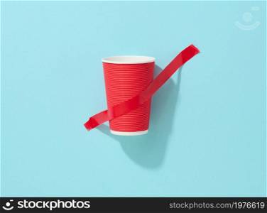 red cardboard cup glued with red sticky tape to the blue background