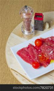 Red carpaccio with tomatoes over a white plate