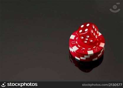 Red casino dice and chips isolated over black reflective background.. Red casino dice and chips isolated over black reflective background