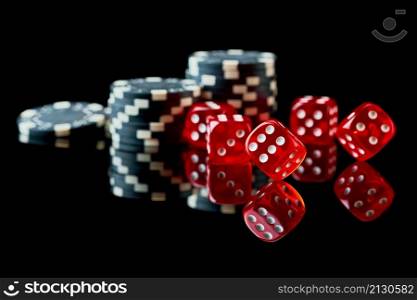 Red casino dice and chips isolated over black reflective background.. Red casino dice and chips isolated over black reflective background