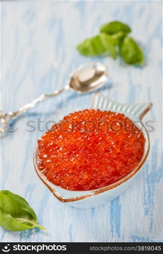 Red caviar in fish-shape bowl, closeup, selective focus