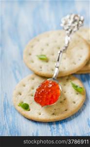 Red caviar in spoon on crackers, closeup, selective focus