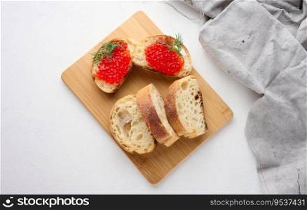 Red caviar on slices of white wheat bread on a white table, concept of luxury and gourmet cuisine