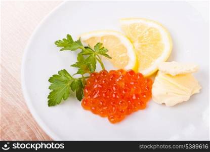 Red caviar snack on white plate with lemon and butter
