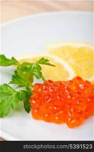 Red caviar snack on white plate with lemon and butter