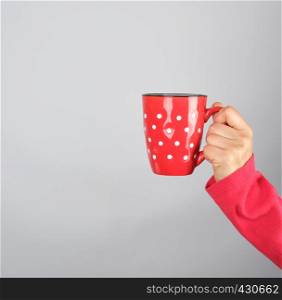 red ceramic cup in a female hand on a white background, copy space