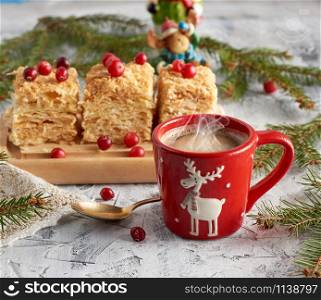 red ceramic cup with black coffee and slices of puff cake Napoleon with butter cream decorated with cranberries, festive backdrop