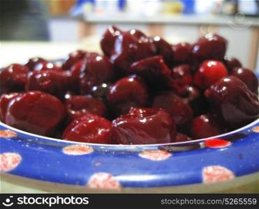 Red cherries on the white plate with a blue edging