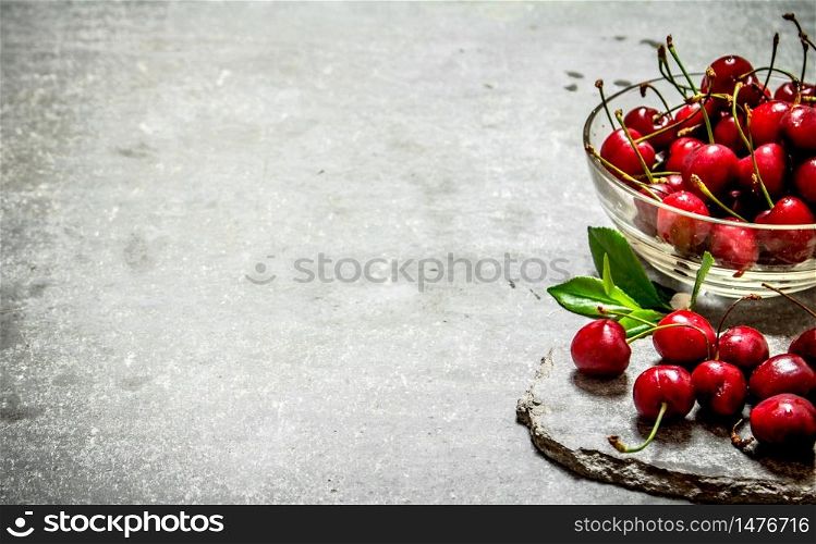 Red cherry in the Cup. On the stone table.. Red cherry in the Cup.