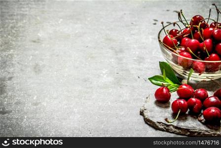 Red cherry in the Cup. On the stone table.. Red cherry in the Cup.