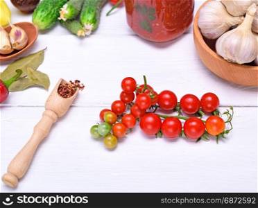 Red cherry tomatoes and spoon with spices on white background, top view