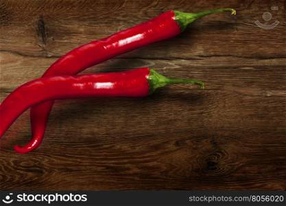 Red chili pepper isolated on wooden background.