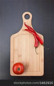 Red chili peppers and tomato on a cutting board