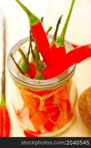 red chili peppers on a glass jar over white wood rustic table