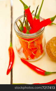 red chili peppers on a glass jar over white wood rustic table