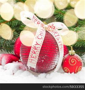 red christmas ball balls with bow in snow under fir tree border on white. red christmas balls in snow
