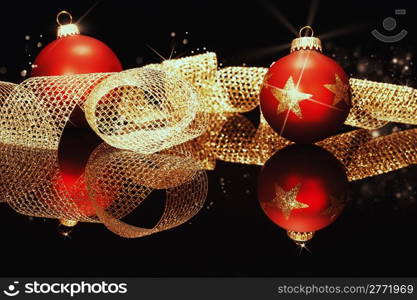 red christmas balls with golden metal ribbon. red christmas balls with glitter stars with golden metal ribbon on a black mirror