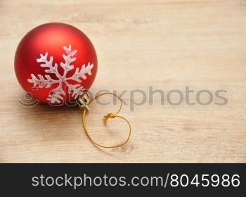 Red Christmas bauble with silver star isolated on a wooden