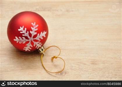 Red Christmas bauble with silver star isolated on a wooden