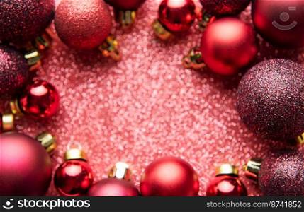 Red Christmas baubles decoration on red shiny background with copy space.