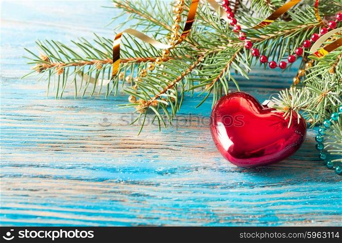 Red Christmas decoration and fir branch on a blue wooden background