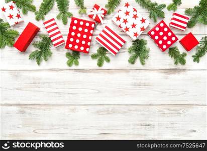 Red Christmas decoration, gifts and pine tree branches on bright wooden background