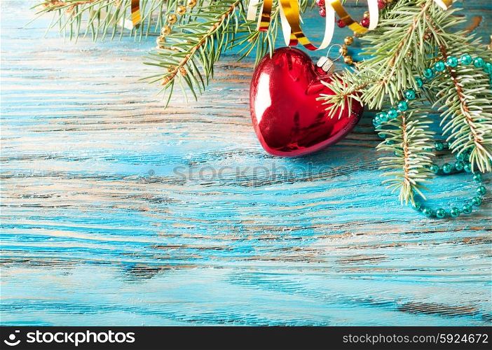 Red Christmas decorations and fir branch on a blue wooden background