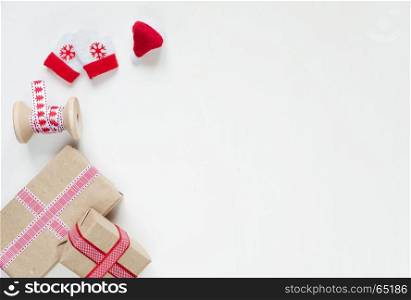 Red Christmas frame, consisting of gift boxes tied with ribbons, Santa's glove and mittens on a white background with space for text. Flat lay composition for greeting cards, websites, social media, magazines, bloggers, artists etc. Christmas wallpaper