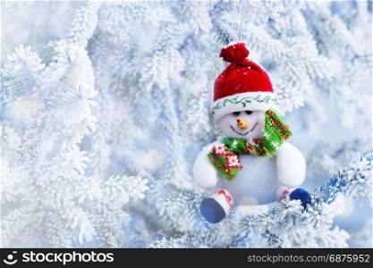 Red Christmas Snowman Hanging on a Tree Branch in the Snow Winter Forest