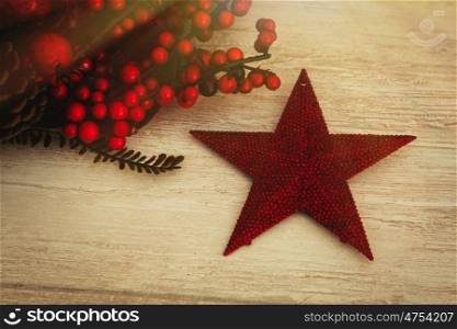 Red Christmas star and berries on wooden background