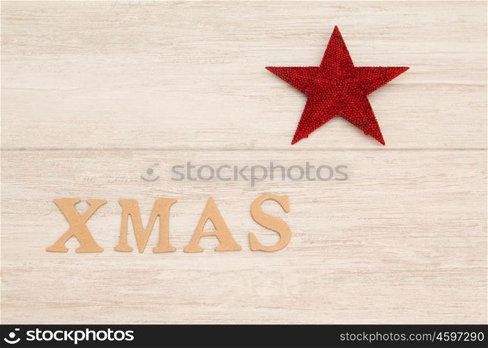 Red Christmas star on gray wooden background with the word Xmas