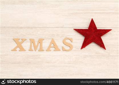 Red Christmas star on gray wooden background with the word Xmas