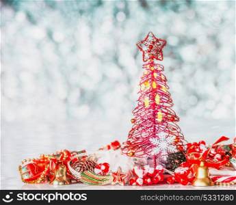 Red Christmas tree with star and festive decorations on blue bokeh background, front view