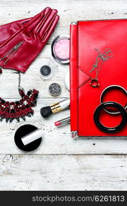 Red clutch bag and ladies accessories. Fashionable ladies handbag with cosmetics and decorations on light background