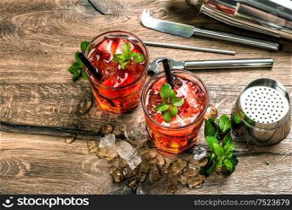 Red Cocktail with strawberry, mint leaves, ice. Drink making bar tools