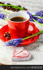 Red coffee cup on a wooden tray covered with flowers of hyacinth. coffee and flowers