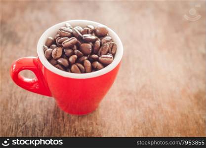 Red coffee cup with coffee beans on wooden table, stock photo
