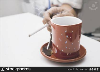 Red coffee cup with hand holding a cigarette