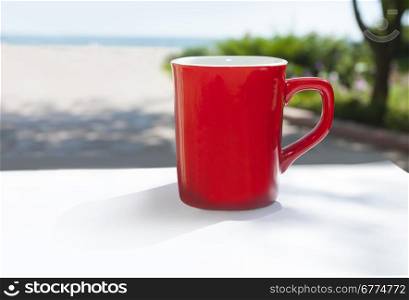 Red coffee mug overlooking the sun shine