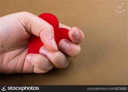 Red color heart shaped object in hand on dotted paper