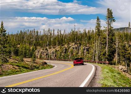 Red convertible sport car on highway in Yellowstone National Park, Wyoming, USA
