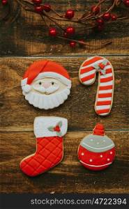 Red cookies for Christmas and a branch with red berries on a wooden background