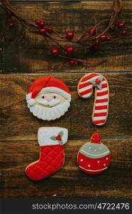 Red cookies for Christmas and a branch with red berries on a wooden background
