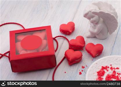 Red cookies in the shape of a heart in a gift box on wooden boards and a plate and decorated with ribbon and angel on Valentine&rsquo;s Day. cookies in the shape of hearts on Valentine&rsquo;s Day