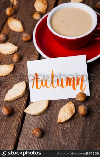 red cup of coffee and leaf shape cookies with the inscription Autumn